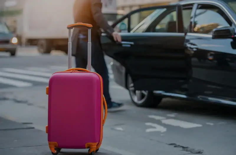Black taxi waiting at the kerb with a suitcase beside it